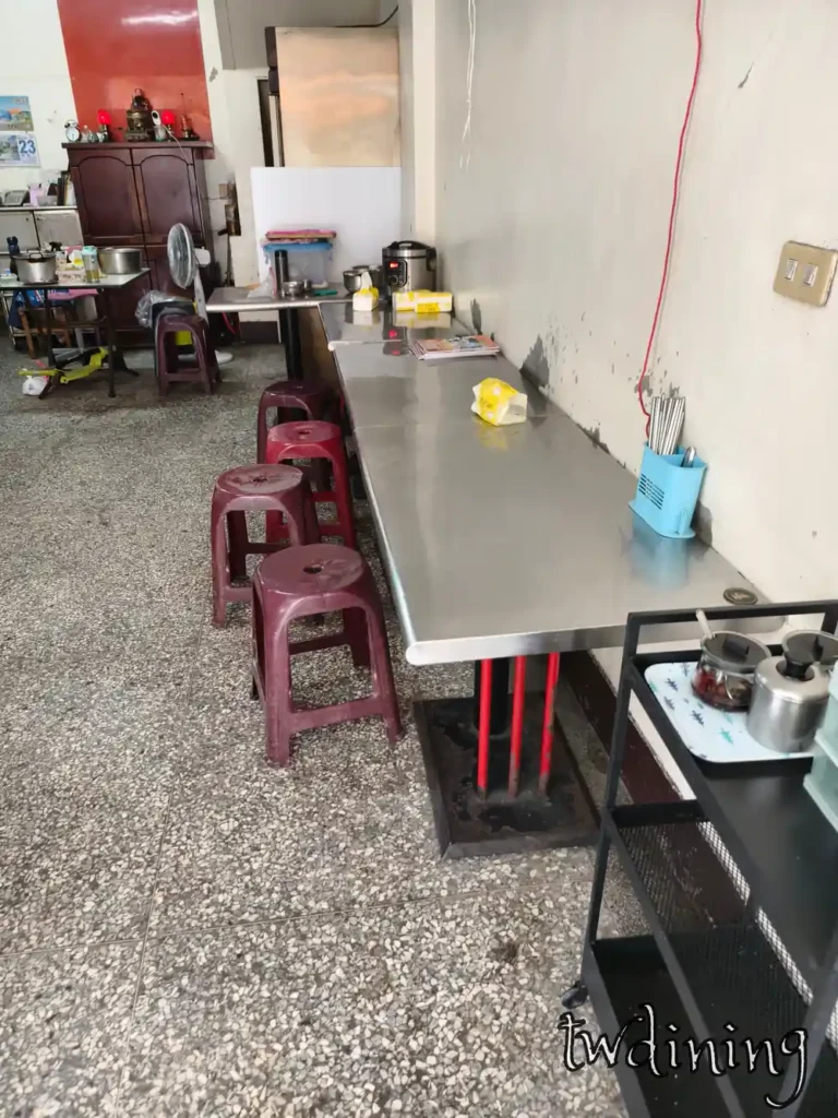 台中北區小吃店內部的 seating area 用餐環境採用傳統不鏽鋼長桌與在地復古磨石子地板空間