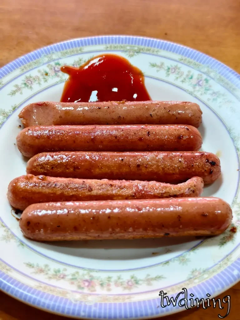 一份 Fried Hot Dogs 煎熱狗淋上 Tomato Ketchup 番茄醬，阿婆早餐 經典 Snack 小點心具有 Meaty Flavor 與極致 Juicy 多汁口感表現。