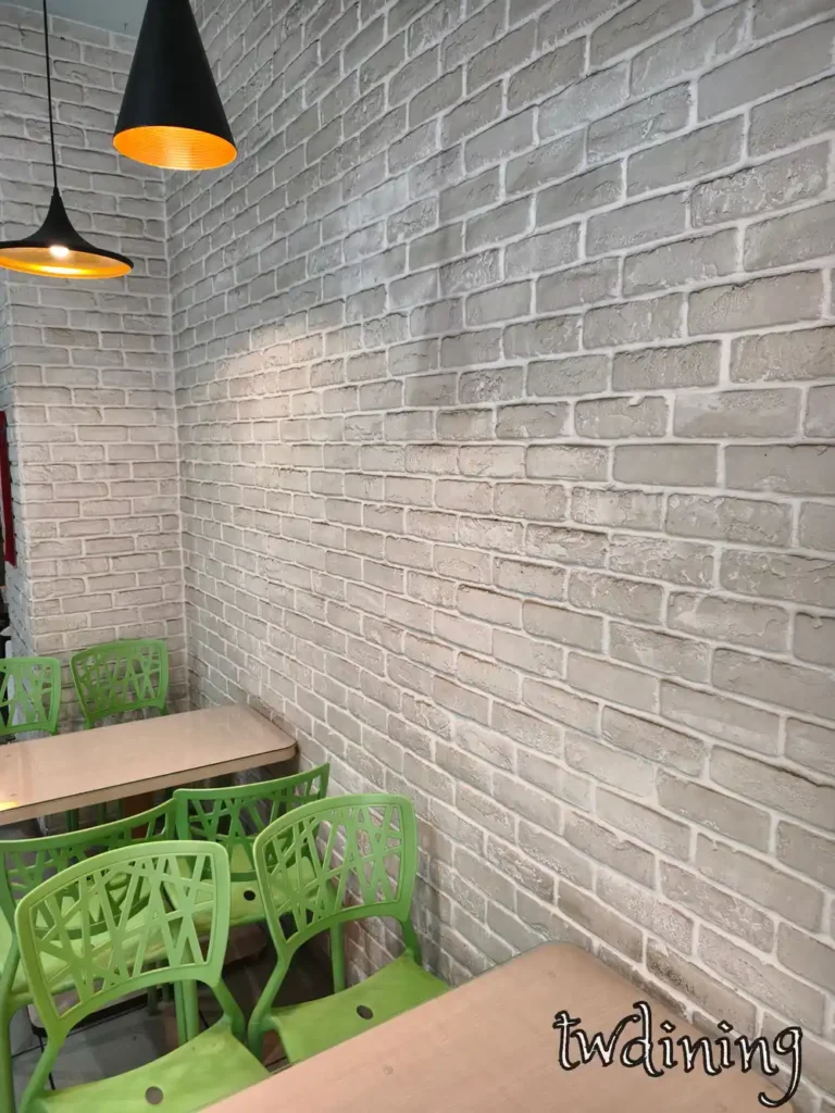 台中北區滿意早點 Man Yi Brunch 內用座位區，白色磚牆搭配綠色座椅與工業風吊燈，營造舒適用餐環境 cozy interior seating with brick wall and green chairs.