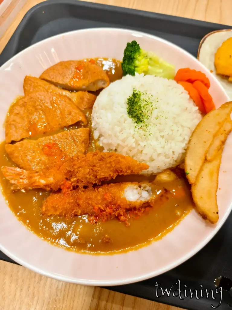 九本家炸蝦咖哩飯拼盤包含兩隻金黃酥脆炸蝦、半月型馬鈴薯塊與白飯，搭配深橘色咖哩醬汁、青花菜與紅蘿蔔，展現日式餐廳炸物定食的客觀視覺元素與擺盤層次。