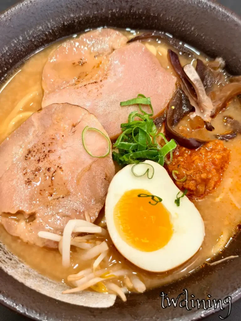 九本家肉醬札幌味噌拉麵實拍，包含兩片叉燒與特製味噌肉醬，搭配半熟蛋、黑木耳絲與蔥花，展現道地札幌風味的濃厚橘色湯頭與豐富擺盤質感。