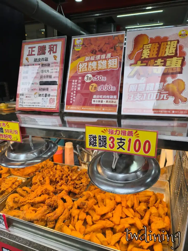 正騰和炸雞櫃檯特寫，上方張貼招牌雞翅與雞腿 3 支 100 元大特惠海報，下方展示櫃擺滿金黃酥脆的炸物與現炸地瓜薯條等熱銷產品。