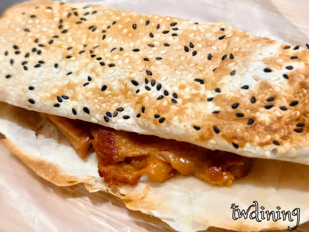 Flaky-texture 燒餅 with teriyaki chicken filling. The golden-brown crust is crispy-edges. 酥脆燒餅夾入嫩煎雞排，每一口都 succulent-meat 與 savory aroma，展現傳統早餐視覺精髓與 rich flavor.