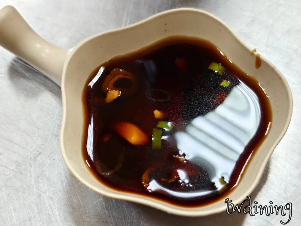 郭家特製 spicy sauce 沾醬。醬油加蔥花與辣椒。米色小碗盛裝手作風味。呈現醬汁光澤與佐料細節。水餃必備辛香料視覺