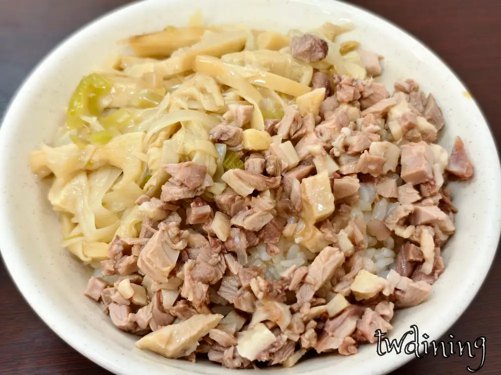 贊鴨招牌鴨肉飯。米白色瓷碗裝盛手工切丁帶皮鴨肉，搭配大量鮮嫩黃色滷筍絲配菜，淋上香醇鴨油的白飯顆粒分明，精準呈現豐盛台式小吃視覺精髓與食材堆疊層次感。