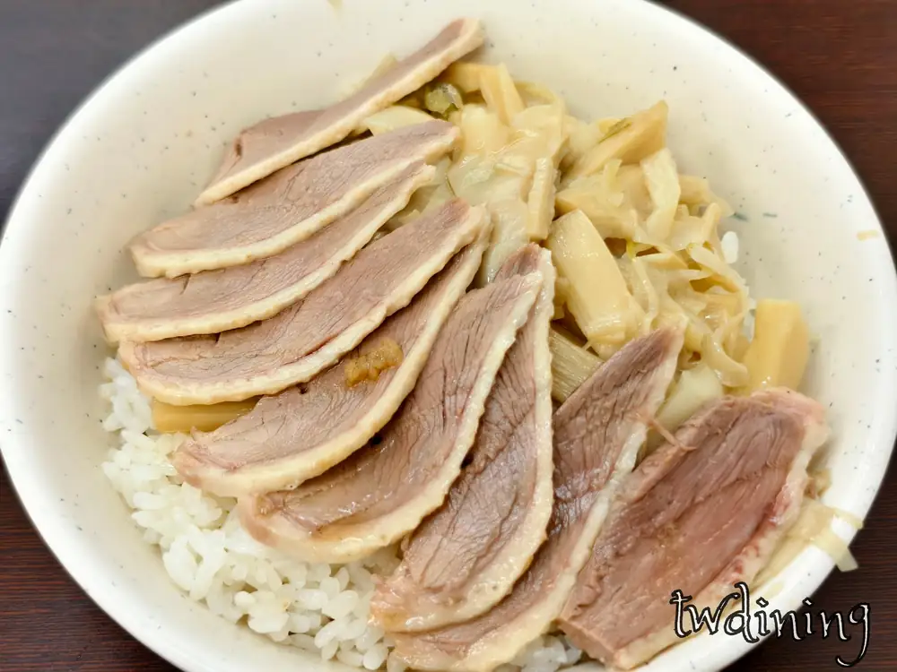 贊鴨招牌鴨肉片飯。整齊排列的粉嫩帶皮鴨肉切片鋪在白飯上，搭配特製滷筍絲配菜，展現鴨肉肉質紋理與多汁色澤，精準描述台式精緻鴨肉飯的視覺細節、食材排列與誘人的油脂分布感。